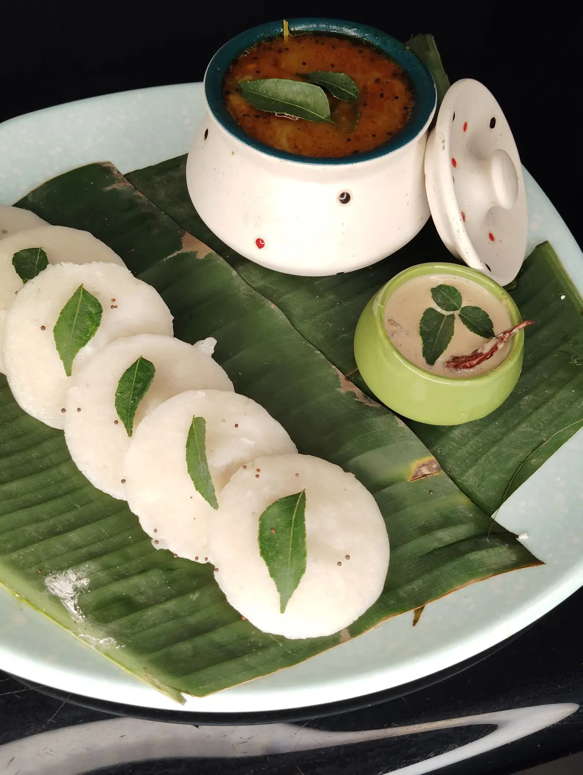 Soft idlis on a banana leaf with sambar and chutney